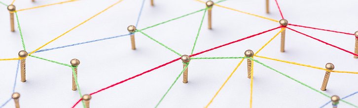 Nägel auf einem Brett, zwischen denen ein Netz gespannt ist