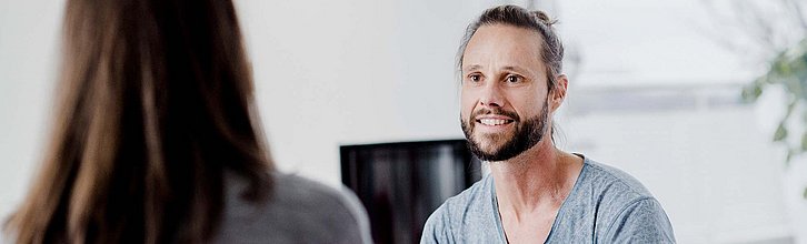 zwei menschen miteinander im Gespräch, eine Person ist nur von hinten zu sehen