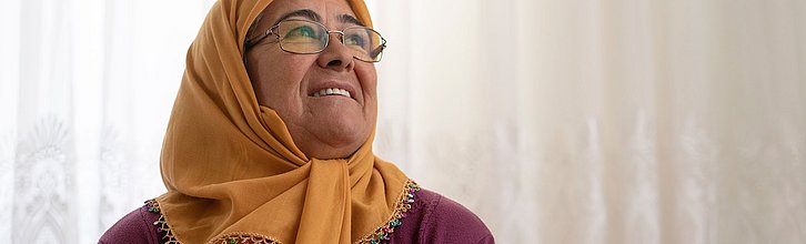 Eine Frau mit einem Kopftuch lächelnd